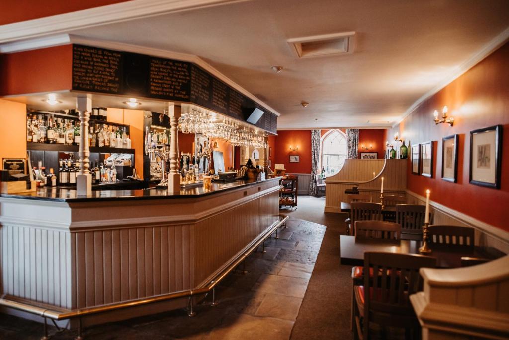 The long bar at the Boar's Head, warm orange walls, hanging glasses and a stone-flagged floor.