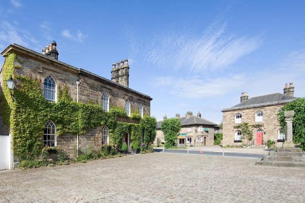 The ivy-covered stone frontage of the Boar's Head on a cobbled square in Ripley, under a blue sky.