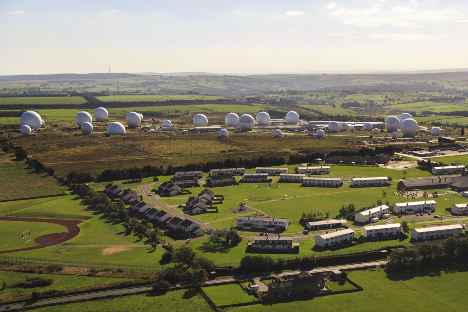 Aerial view of RAF Menwith Hill: dozens of white radar domes and low buildings among green Yorkshire fields.